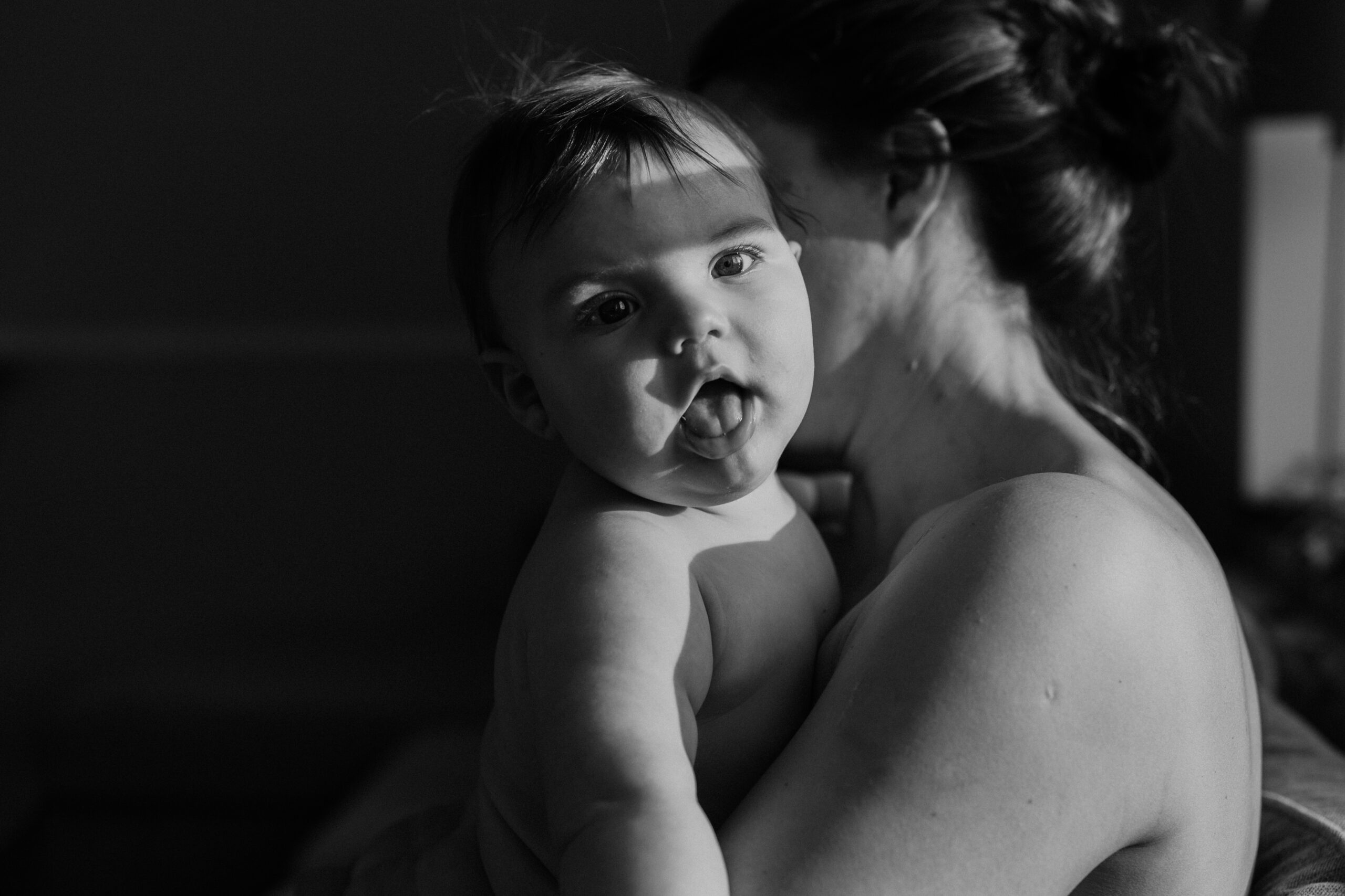 bebis och mamma sitter tillsammans och solen lyser i barnets ansikte